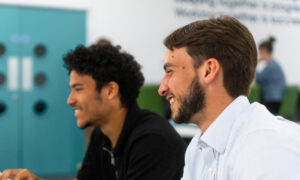 Two male marketing executive apprentices working together at a computer