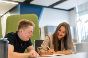 Male and female marketing executive apprentices working on a piece of writing